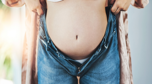 a pregnant strecthing jeans upward