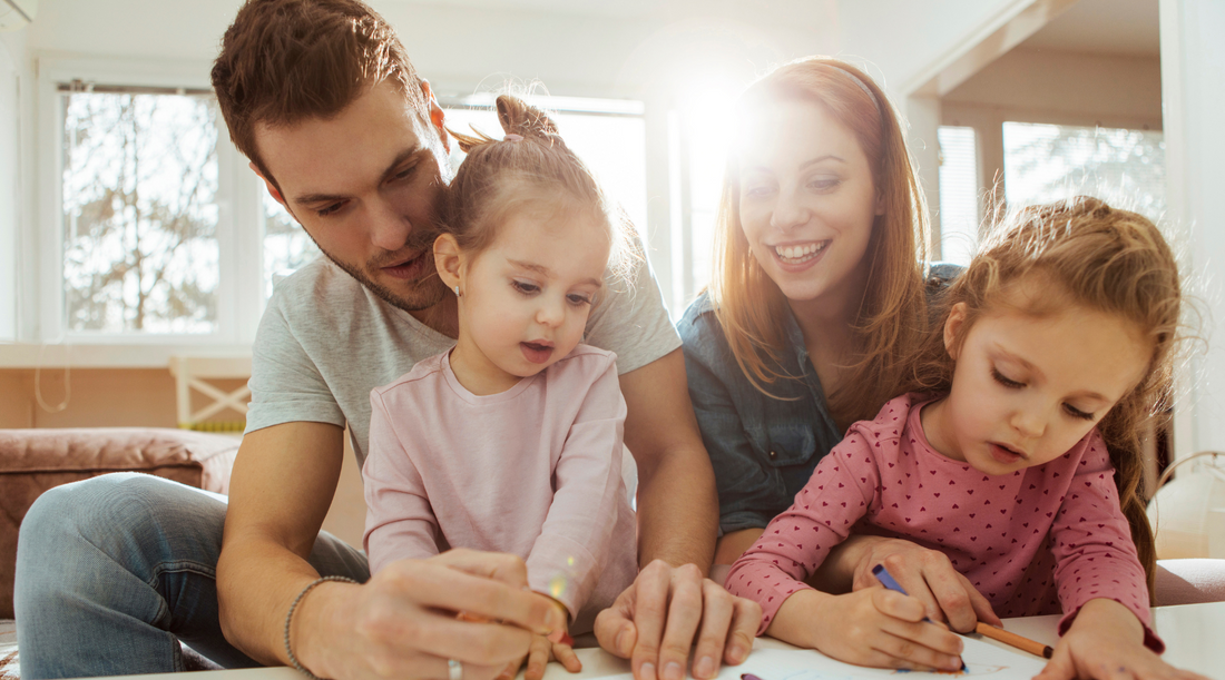 a family is sitting at a table drawing together