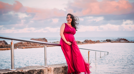 A pregnant woman in red posing outdoors for pregnancy photoshoot