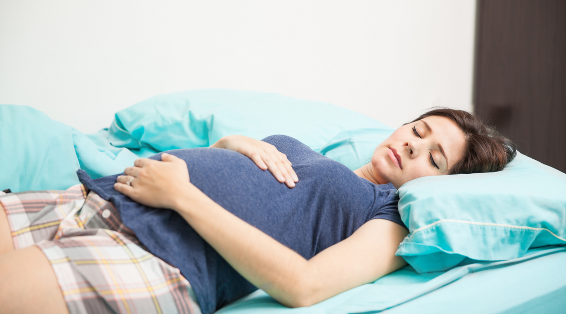 pregnant woman sleeping on her back while holding her baby belly